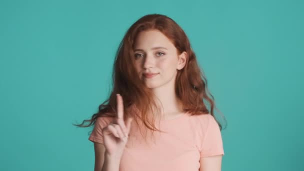 青い背景の上にカメラに自信を持ってジェスチャーを示さない魅力的な赤毛の女の子 意見の相違 — ストック動画