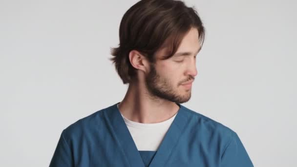 若い魅力的な男性医師は 白い背景の上にしっかりと医療マスクを脱ぎます 安全コンセプト — ストック動画