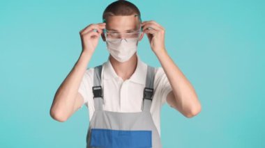 Renkli arka planda maske takan ve koruyucu gözlük takan profesyonel bir müteahhit.