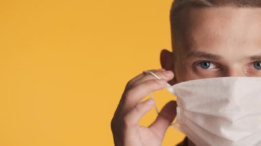 Tıbbi maske takan genç mavi gözlü adamı kapat ve renkli arka plan üzerinden fotokopi odasına bak. Önce güvenlik kavramı