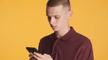 Çekici, gelişigüzel sarışın adam renkli arka planda akıllı telefon kullanıyor.