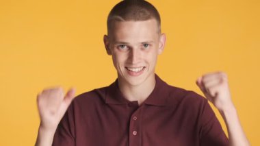 Çekici, heyecanlı adam. Renkli arka planda duygusal olarak evet işareti yapıyor.
