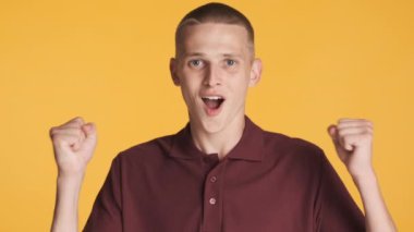 Çekici, neşeli adam renkli arka planda kameraya seviniyor. Başarı ifadesi