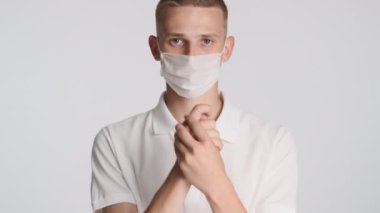 Tıbbi maskeli yakışıklı adam beyaz arka planda kamerada ellerini yıkıyor. Önce güvenlik kavramı