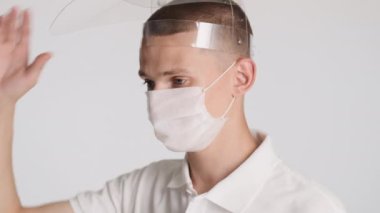 Tıbbi maskeli yakışıklı, beyaz arka planda koruyucu maske takıyor. Güvenlik kavramı
