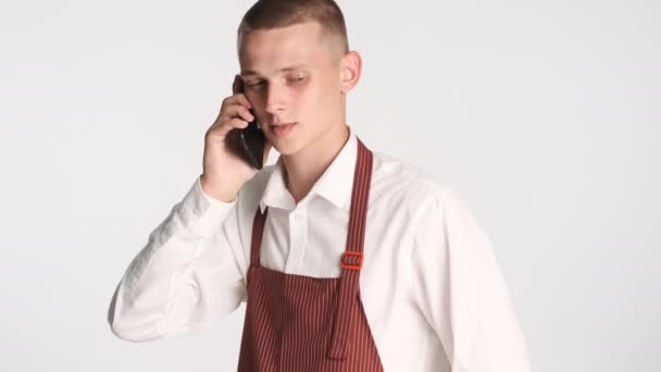 Mladý Atraktivní Číšník Uniformě Přestat Mluvit Smartphone Přes Bílé Pozadí — Stock video
