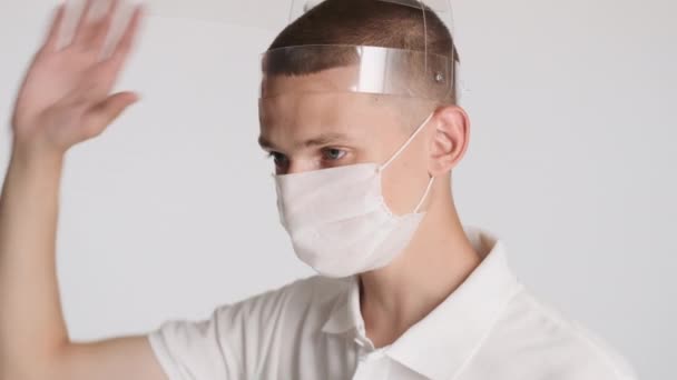 隔離されたカメラの保護マスクを身に着けている医療用マスクで魅力的な男のサイドビューショット 安全コンセプト — ストック動画
