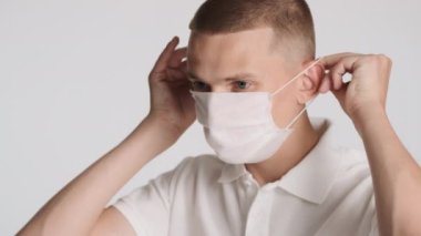 Beyaz arka planda tıbbi maske takan çekici bir adamın yan görüntüsü. Güvenlik kavramı