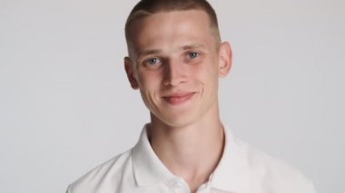 Yakışıklı mavi gözlü adam beyaz arka planda kamerada mutlu bir şekilde gülümsüyor. Mutlu ifade