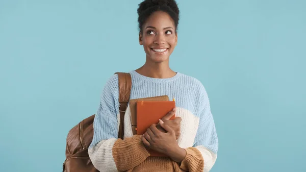 漂亮的微笑着的非洲裔美国女学生 带着书本 快乐地将五彩斑斓的背景抛在一边 — 图库照片