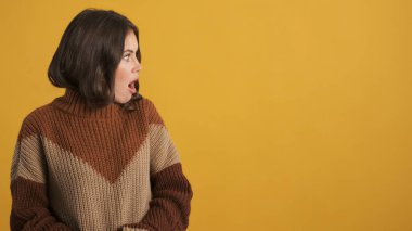 Şok olmuş güzel esmer kız, örgü süveter ile inanılmaz bir şekilde renkli arka plan üzerinden fotokopi odasına bakıyor.