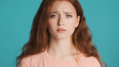 Üzücü bir şekilde renkli arka planda kameraya bakan, gücenmiş kızıl saçlı kızı yakından çek. İfadeyi boz