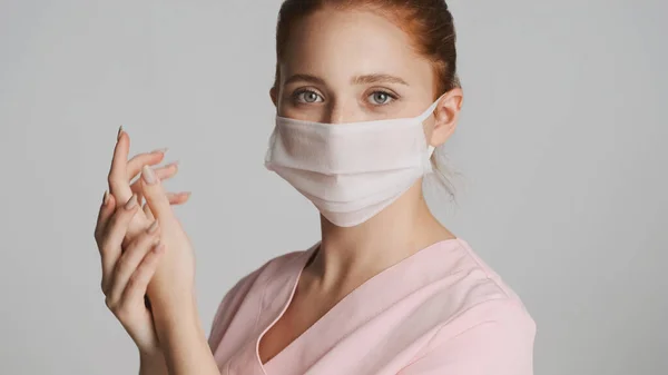 Young nurse in medical mask washing hands on camera isolated. Safety first concept