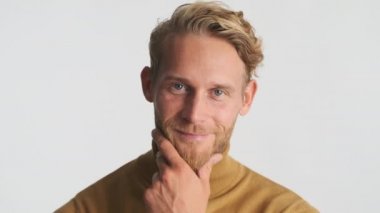 Yakışıklı, sarışın, sakallı adam kameraya güvenli bir şekilde poz veriyor. Çekici erkek model stüdyoda poz veriyor.