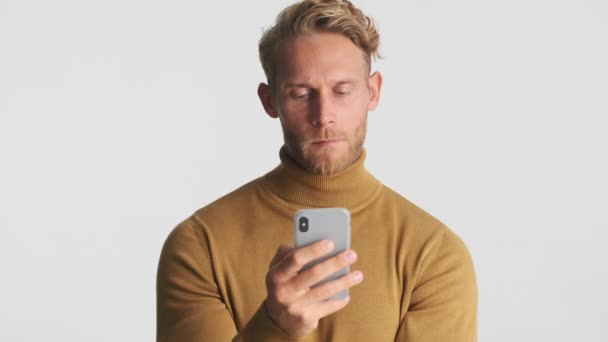 Atraktivní Vážné Blond Vousatý Muž Záměrně Pomocí Smartphone Přes Bílé — Stock video