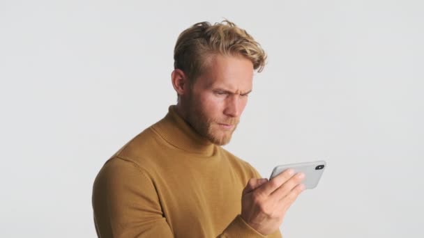 Handsome Serious Blond Bearded Man Frustratedly Watching Video Smartphone Isolated — Stock Video