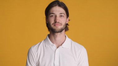 Genç, çekici, sakallı bir adam renkli arka planda kameraya iyi bir jest yapıyor. Aferin ifade.