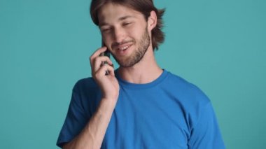 Çekici sakallı adamın portresi akıllı telefondan renkli arka planda konuşuyor.