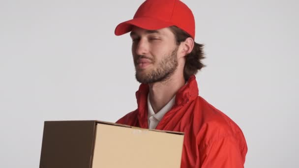 迷人而快乐的快递员 头戴红帽子 身穿夹克衫 手里拿着送货箱 高兴地看着被隔离的相机 服务概念 — 图库视频影像
