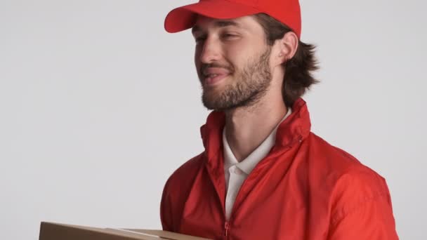 漂亮的红帽送货员高兴地在白色背景的相机上送货箱 — 图库视频影像