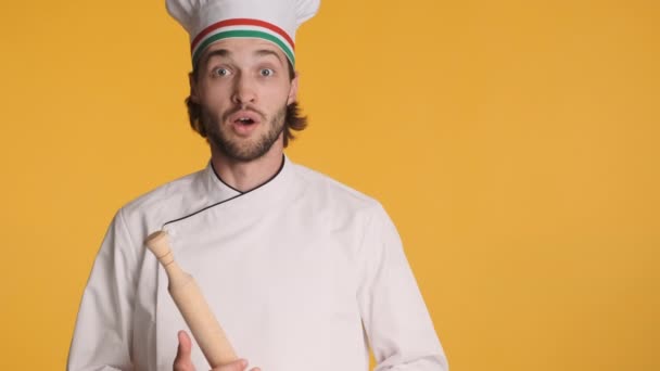 引人注目的意大利职业厨师穿着制服 在五彩缤纷的背景下 在镜头前表现出贝尔利索的手势和滚动式的别针 — 图库视频影像