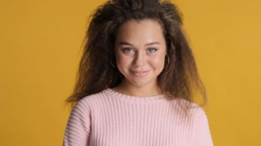 Çekici esmer kızın portresi mutlu bir şekilde sarı arka planda poz veriyor. Neşeli ifade