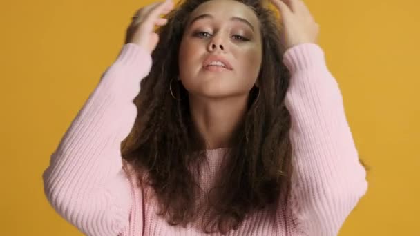 可愛いですブルネット女の子魅力的に再生とともに毛の上のカメラ上の黄色の背景 — ストック動画