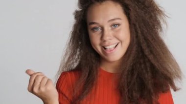 Çekici, heyecanlı esmer kız beyaz arka planda izole edilmiş para hareketi yapıyor.