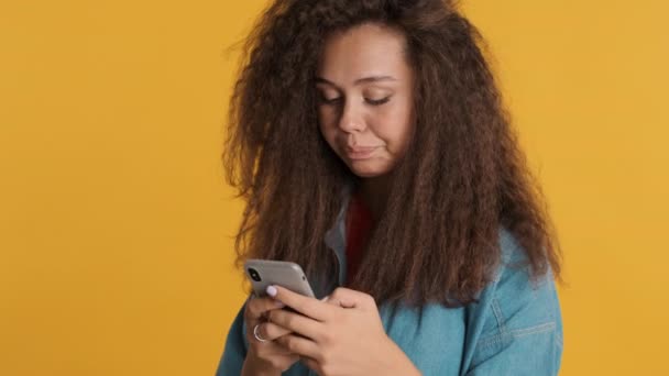 Soustředěná Brunetka Dychtivě Píše Zprávy Smartphonu Izolovaném Žlutém Pozadí Koncept — Stock video