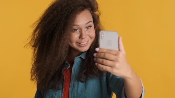 美丽的黑发女孩与好友愉快地通过智能手机进行视频通话 背景五彩缤纷 现代技术概念 — 图库视频影像