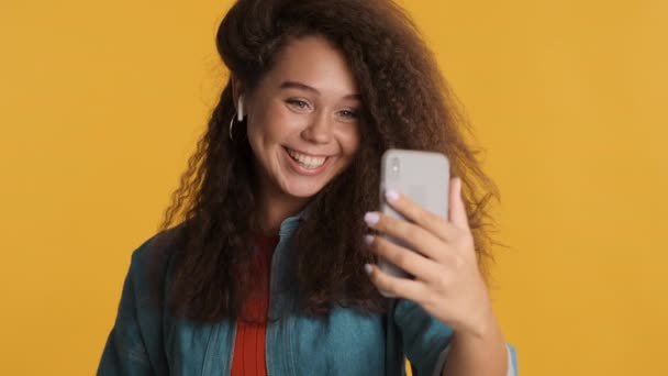 Çekici Esmer Kız Sarı Arka Planda Izole Edilmiş Akıllı Telefonu — Stok video