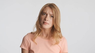 Şüpheli sarışın kız beyaz arka planda izole edilmiş kameraya dikkatlice bakıyor. Ne ifadesi?