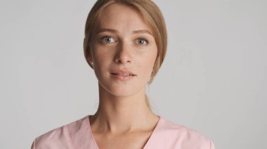 Güzel sarışın doktorun portresi beyaz arka planda kameraya şehvetle bakıyor.