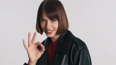 Kısa saçlı ve kırmızı dudaklı güzel bir kız arkadaşının planını kabul ediyor ve beyaz arka planda kameranın karşısına geçiyor. Vücut dili kavramı