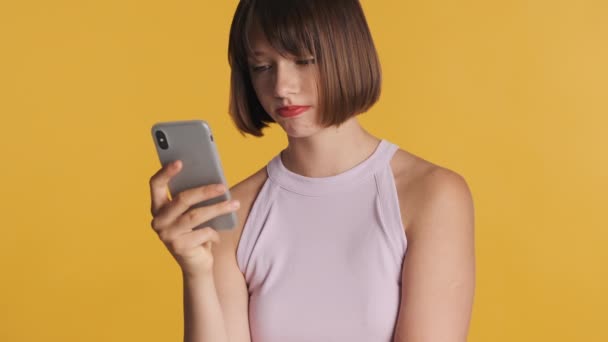 头发蓬乱 看起来很伤心的黑发女孩在智能手机上通过五颜六色的背景得到男朋友的留言 — 图库视频影像