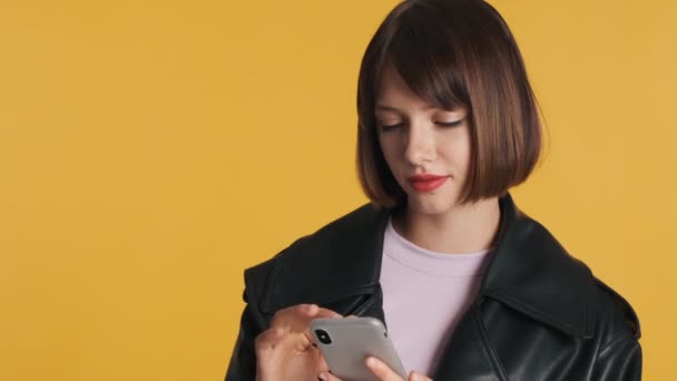 漂亮时髦的黑发女孩专注于智能手机浏览社交网络孤立的黄色背景 现代技术概念 — 图库视频影像