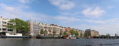Amsterdam, Hollanda - 16 Mayıs 2018: Panoramik mimarisi ve tekneler ve Sarphatistraat Köprüsü yanında Amstel otel Amsterdam şehir merkezinde Amstel Nehri cityscape Doğu Bankası.