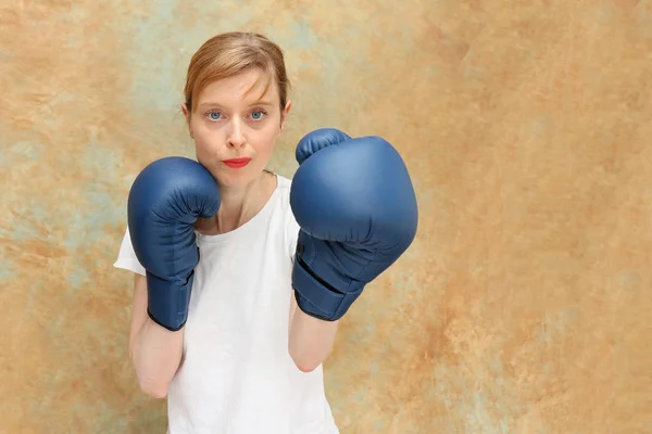 Blonde blue eyed girl with boxing gloves inside studio