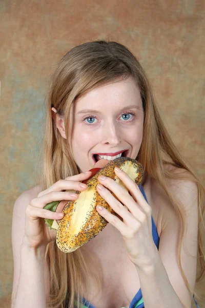 Nuori blondi nainen syö voileipä — kuvapankkivalokuva