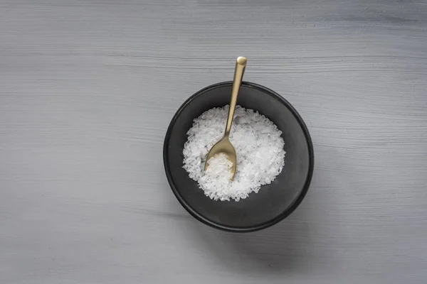 盐片与金勺和黑色碗在灰色表面 — 图库照片