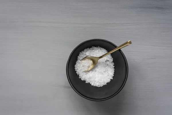盐片与金勺和黑色碗在灰色表面 — 图库照片