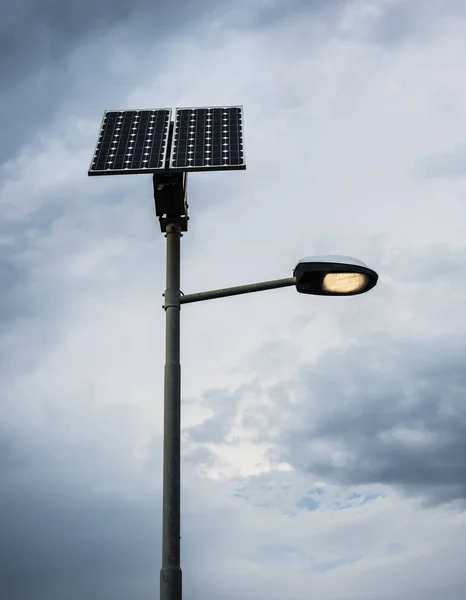 Solarpanel Auf Straßenlaternenmast Mit Eingeschaltetem Licht Und Bewölktem Himmel Stockfoto