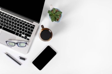 Ofis masaları ile dizüstü bilgisayar, smartphone, kalem, defter ve izole saf beyaz zemin üzerine kahve / dizüstü ve tablet mockup kavramı. (Seçici odak)