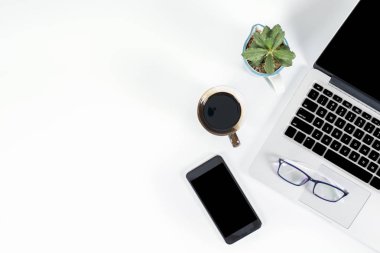 Ofis masaları ile dizüstü bilgisayar, smartphone, kalem, defter ve izole saf beyaz zemin üzerine kahve / dizüstü ve tablet mockup kavramı. (Seçici odak)