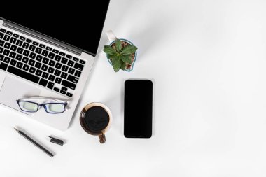 Ofis masaları ile dizüstü bilgisayar, smartphone, kalem, defter ve izole saf beyaz zemin üzerine kahve / dizüstü ve tablet mockup kavramı. (Seçici odak)