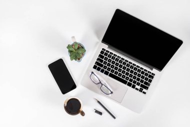 Ofis masaları ile dizüstü bilgisayar, smartphone, kalem, defter ve izole saf beyaz zemin üzerine kahve / dizüstü ve tablet mockup kavramı. (Seçici odak)