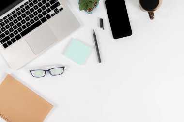 Ofis masaları ile dizüstü bilgisayar, smartphone, kalem, defter ve izole saf beyaz zemin üzerine kahve / dizüstü ve tablet mockup kavramı. (Seçici odak)