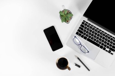 Ofis masaları ile dizüstü bilgisayar, smartphone, kalem, defter ve izole saf beyaz zemin üzerine kahve / dizüstü ve tablet mockup kavramı. (Seçici odak)