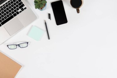 Ofis masaları ile dizüstü bilgisayar, smartphone, kalem, defter ve izole saf beyaz zemin üzerine kahve / dizüstü ve tablet mockup kavramı. (Seçici odak)