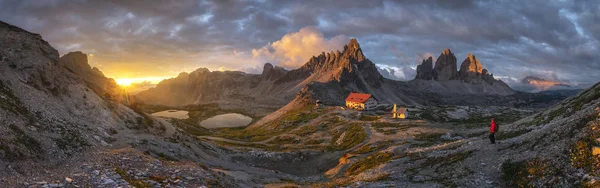 Tre Cime, Dolomites, İtalya gün batımında altın gökyüzü ile ev ve dağ Manzaralar panorama görünümü. — Stok fotoğraf